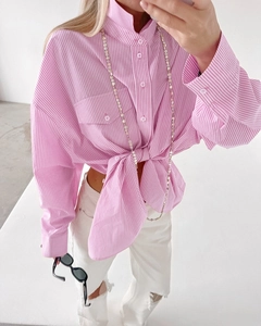 Detail of pink striped cotton shirt featuring a front-tie waist and functional chest pockets