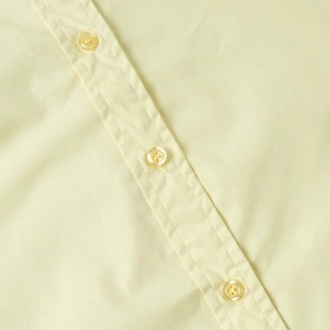Detailed close-up of light yellow cotton shirt featuring high-quality resin buttons