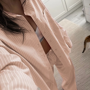 Detail of pink and white striped pajama set with loose long-sleeve shirt and cozy trousers