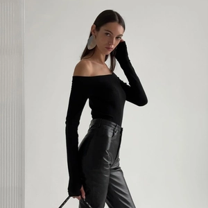 Detail of elegant black off-shoulder slim-fit long-sleeve top with glossy leather pants