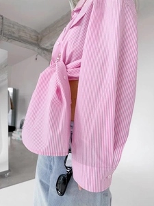 Detail of pink and white striped cotton shirt featuring a stylish front knot hem design