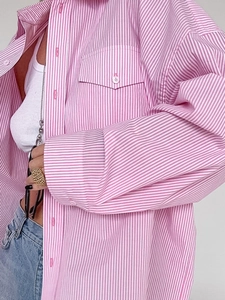 Detail of pink striped shirt with front pocket and chic glasses hanging on the collar