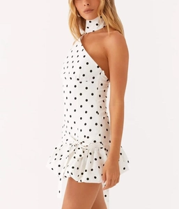 Detailed view of white polka dot dress with off-shoulder cut and ruffled bow hem