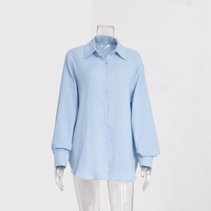 Dettaglio del tessuto in crepe di cotone azzurro della camicia con bottoni e colletto