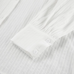 Detailed close-up of white cotton jacquard shirt cuff with double button closure and texture