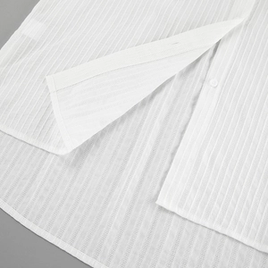 Detail view of white cotton jacquard fabric with textured patterns and clean stitching