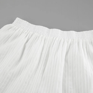 Detail view of white cotton jacquard fabric with vertical stripes and elastic waistband