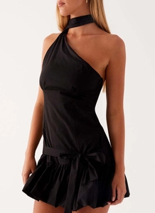 Close-up of black one-shoulder halter dress featuring waist bow and ruffled hemline