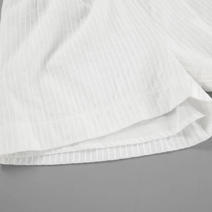 Detailed view of white cotton jacquard fabric with vertical texture and precise stitching