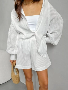 Detail of white cotton jacquard fabric texture on loose-fit long sleeve shirt and shorts