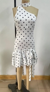Detailed close-up of a white polka dot dress with layered ruffles and waist bow details