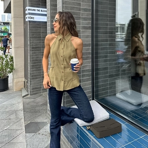 Detail of olive green halter neck button-up shirt and high waist flared blue jeans