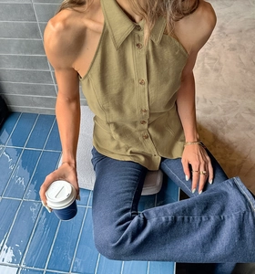 Detail of olive green halter neck vest with brown buttons and blue flare jeans