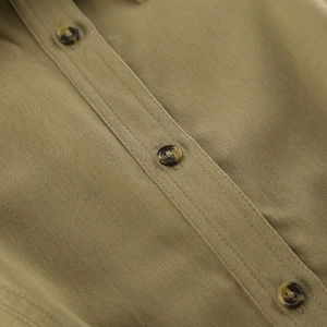 Detail of olive green twill fabric showing brown marble buttons and clean stitching