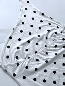 Close-up detail of white and black polka dot dress fabric with elegant draping