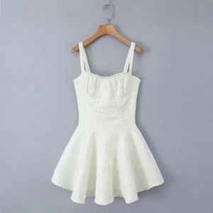 Détails d'une robe trapèze blanche avec broderies florales et finitions en dentelle