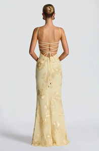 Detail of the backless cream yellow dress featuring intricate floral embroidery and tie-up straps