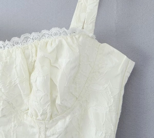 Détail de la robe blanche présentant une texture plissée et de la dentelle fine au décolleté
