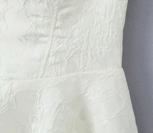 Détail d'une robe blanche avec texture jacquard florale et couture de taille élégante