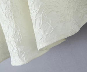 Gros plan du tissu de robe blanc cassé avec texture plissée et détails de couture