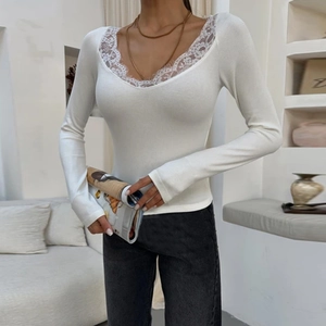 Detailed close-up of delicate eyelash lace trim on the V-neckline of a white ribbed top