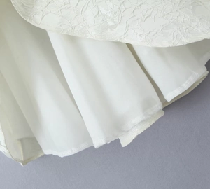 Gros plan sur la texture de dentelle blanche et la doublure en soie d'une robe trapèze