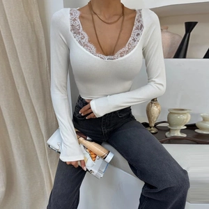 Detailed close-up of white ribbed knit top featuring V-neckline with delicate lace trim