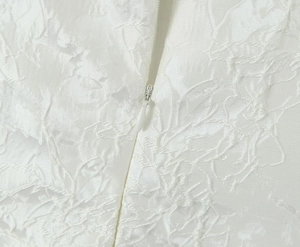 Détail du tissu jacquard blanc avec texture florale et fermeture éclair invisible