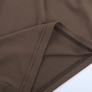 Macro view of brown knit dress hem showing professional double-needle stitching and finish