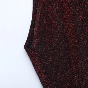 Vue détaillée du tissu métallique rouge scintillant avec coutures et bordures de qualité