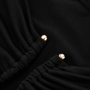 Close-up of black ribbed fabric with ruched detailing and golden metal beads