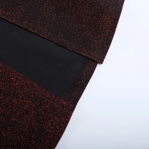 Détail du tissu pailleté rouge-brun et couture noire sur une robe de soirée chic