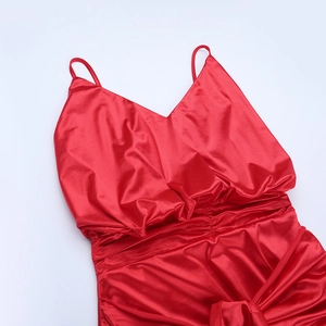 Detailed view of the red satin dress featuring ruched pleats and spaghetti straps