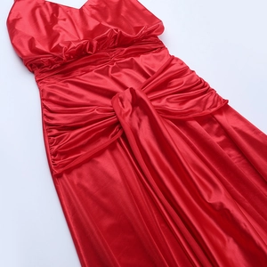 Detailed view of the red satin fabric with elegant ruching texture on the cocktail dress