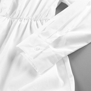Detailed close-up of white cotton shirt cuff with button and elastic waist texture