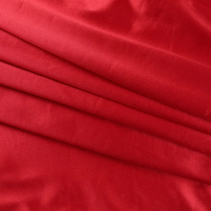 Detailed macro shot of premium red velvet fabric texture with soft metallic silk sheen