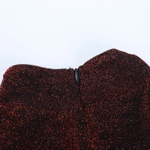 Vue détaillée de la fermeture éclair invisible sur le tissu pailleté rouge de la robe