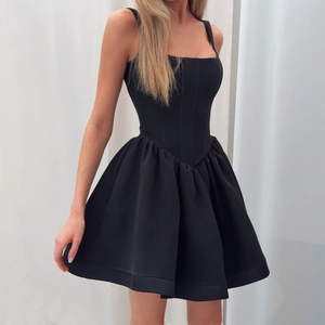 Detail of elegant black strapless cocktail dress with pleated puffy skirt and waist cinching