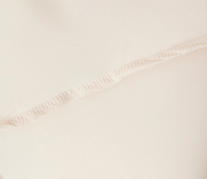 Macro detail of high-quality fine stitching and hem work on the off-white mesh fabric