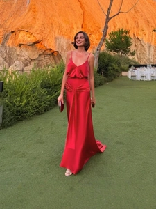 Elegant red satin evening dress with deep V-neck and ruffled waist detail on grass