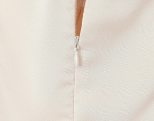 Detail view of a hidden zipper and droplet puller on a ballet-style mesh dress