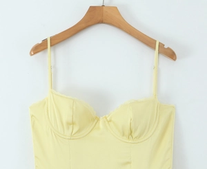 Close-up of delicate lace trim and thin straps on a yellow vintage satin slip dress