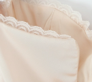 Detail of satin fabric with white lace trim and invisible zipper on the mini dress