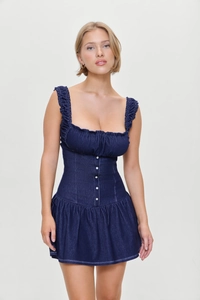 Detail view of navy blue denim mini dress featuring white buttons and ruffle trim straps