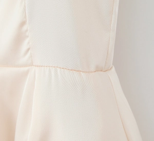 Detail shot of the pleated waist stitching on a pink ballet-style satin A-line dress