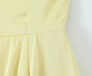 Detailed close-up of light yellow dress waist seam with tulle and woven fabric texture