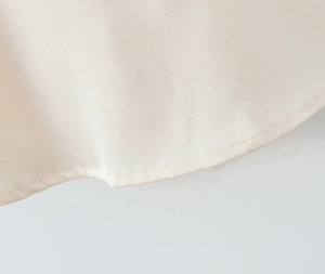 Detailed close-up of the satin hem and layered white mesh on an A-line mini dress