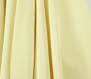 Detailed close-up of pale yellow fabric with elegant texture and vertical drapes