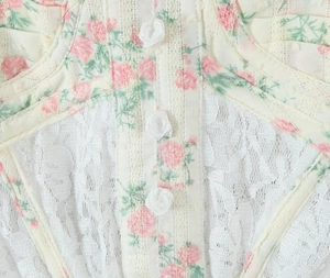 Détail de robe à bretelles fleurie avec patchwork de dentelle et boutons roses 3D