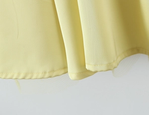 Detail of light yellow dress hem showing silky fabric and delicate mesh tulle layering